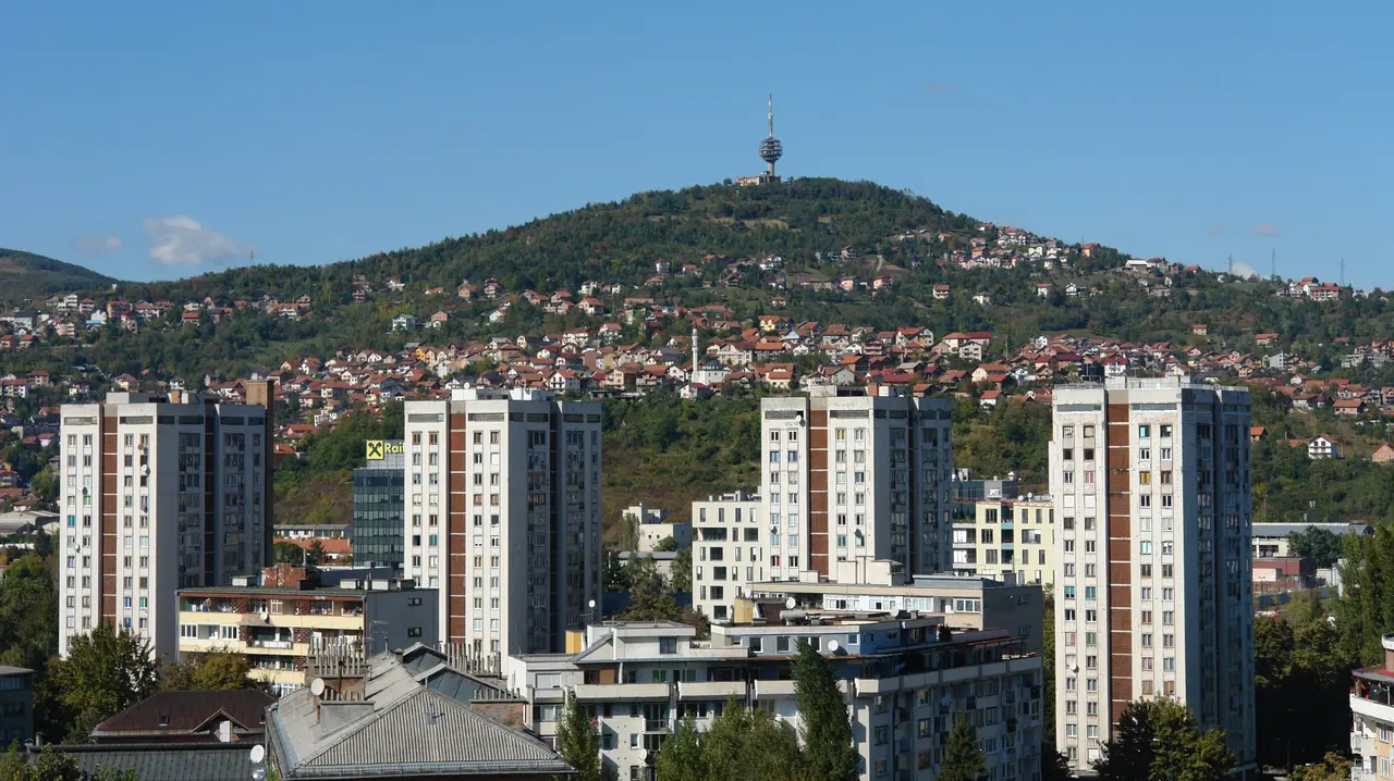 Residential tower blocks and hillside houses in Novo Sarajevo below the wooded Hum hill and its TV tower