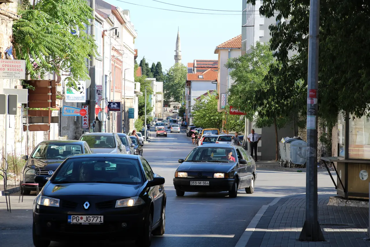 Cars on an ordinary shopping street in Mostar on a summer morning with a minaret at the far end