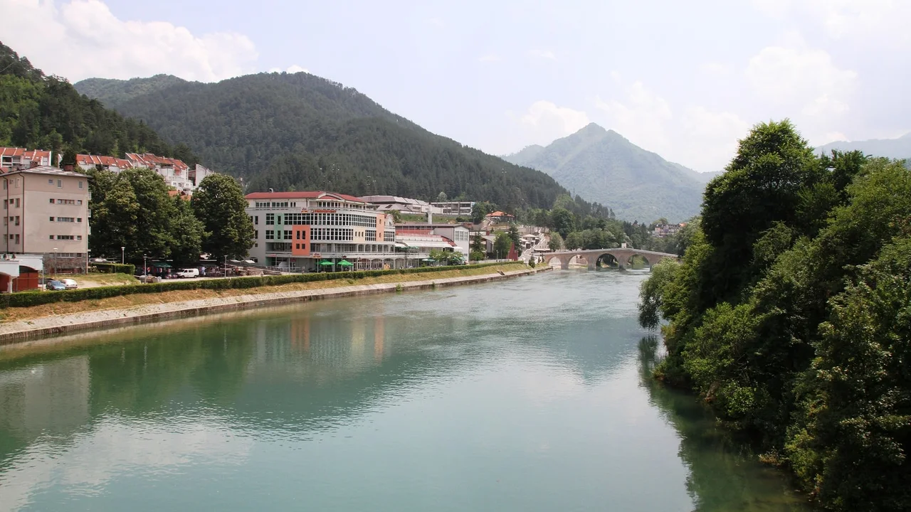 The green Neretva river flowing through Konjic, the town along the left bank and the rebuilt Ottoman stone bridge in the distance