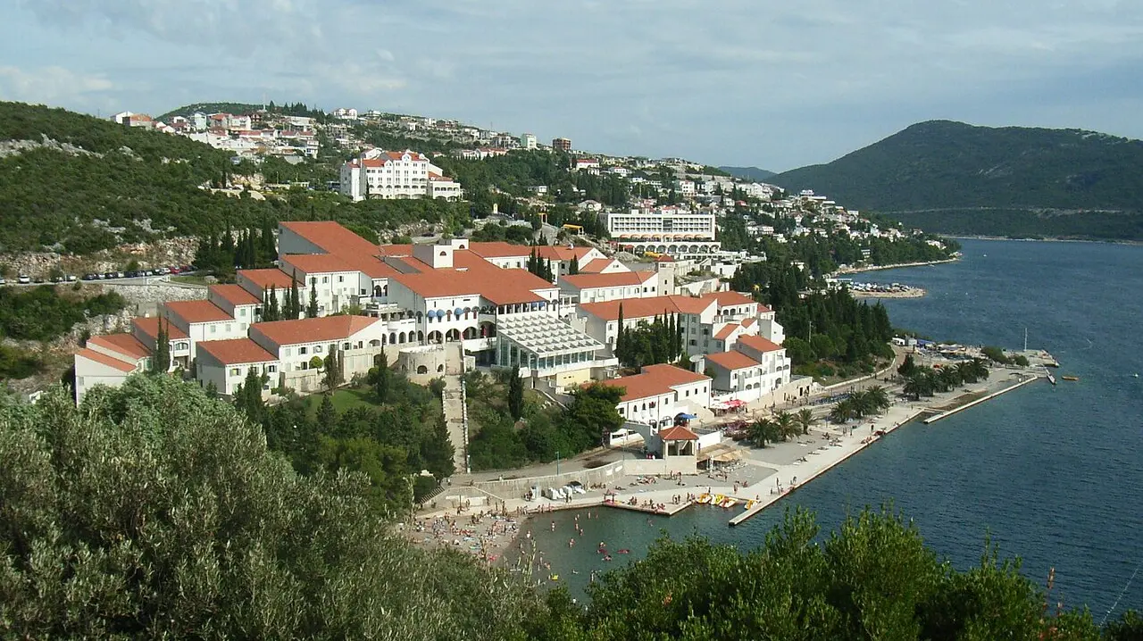 The white red-roofed hotels of Neum terraced down the hillside to a promenade and swimming beach on the blue Adriatic