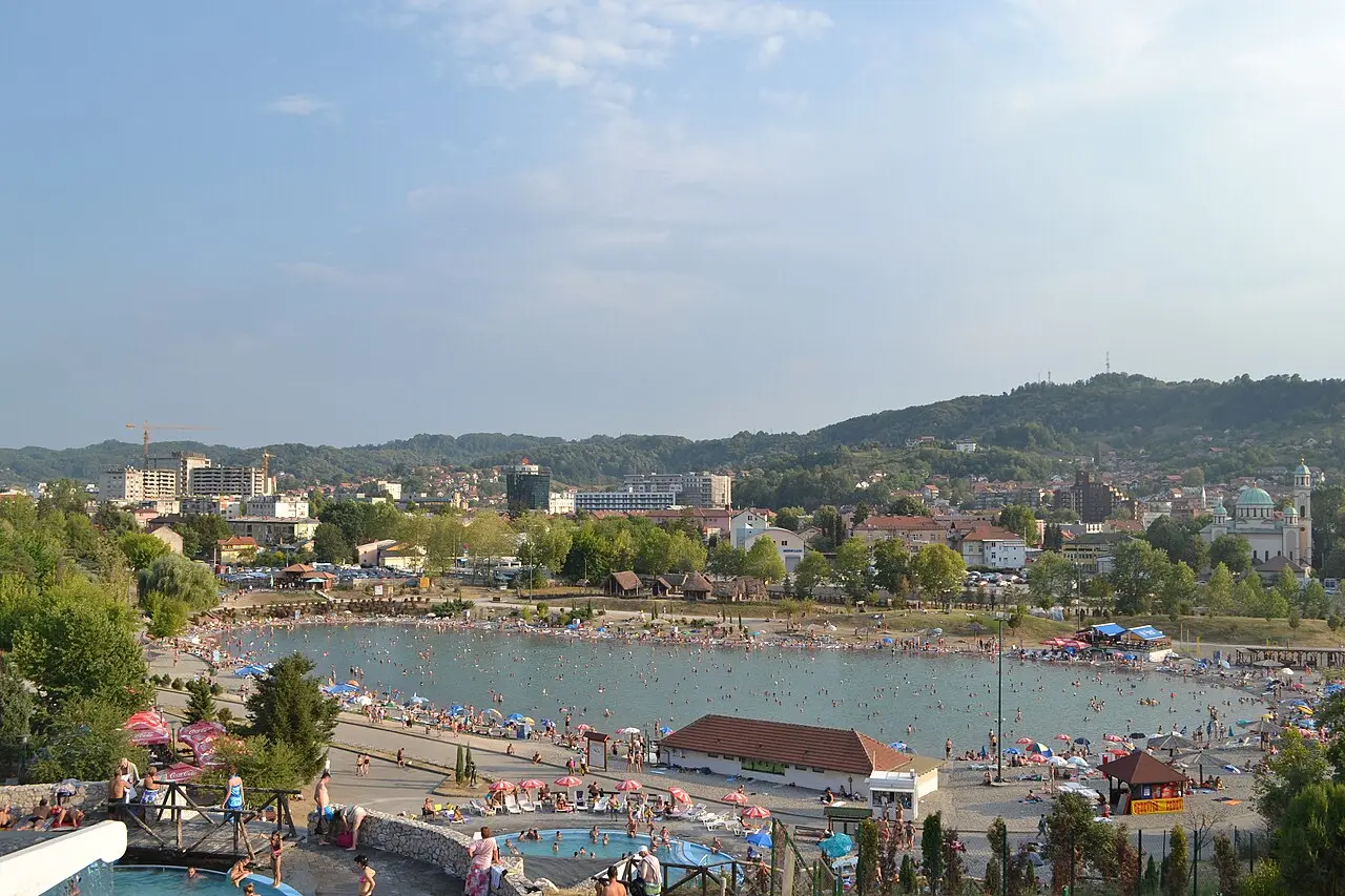 The Pannonian salt lakes in central Tuzla packed with summer swimmers and beach umbrellas, the city and a green-domed cathedral on the hills behind