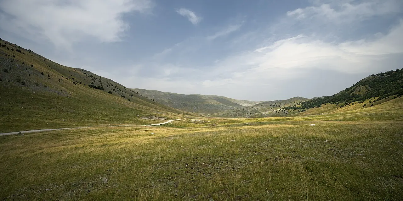 The bare, rolling high plateau of Bjelašnica in summer, pale limestone and green grass running to a distant ridge