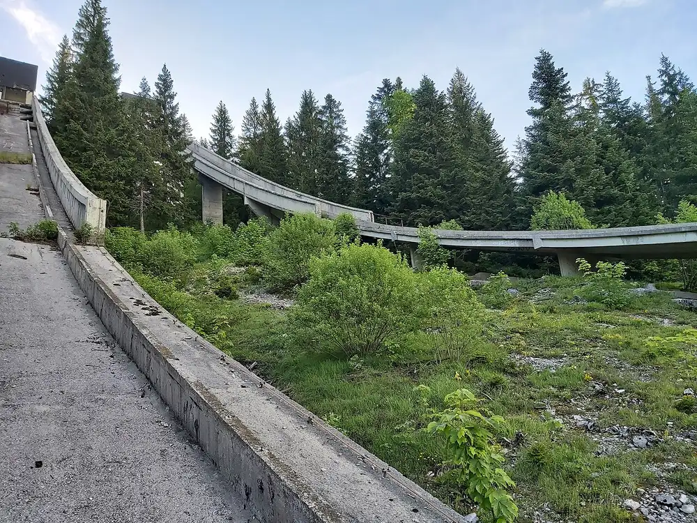 The two derelict concrete ski-jump towers of the Igman Olympic Jumps rising from the forest on Mount Igman