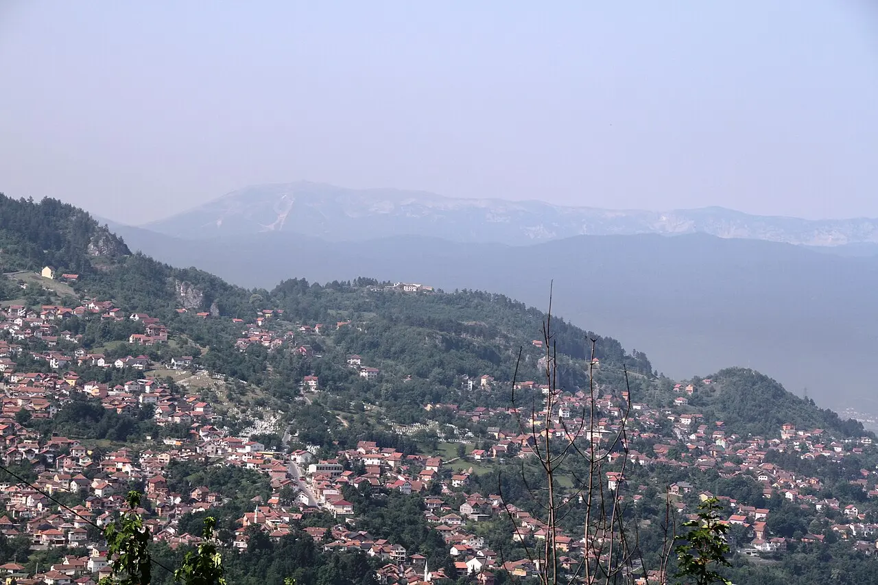 Sarajevo spread along its valley with the long ridge of Bjelašnica mountain rising behind the city under a blue sky