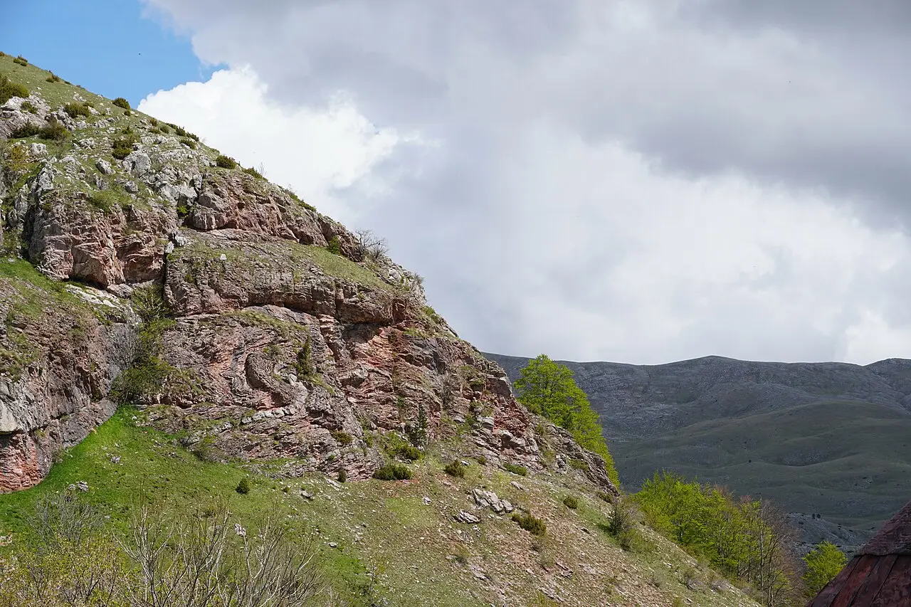 A long fin of folded grey rock on the green hillside above Umoljani, the formation locals call the petrified dragon