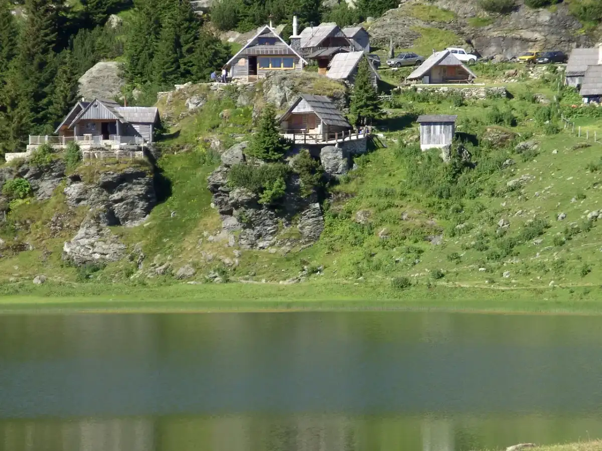 Wooden shepherd huts (katuni) clustered on the slope above Prokoško Lake