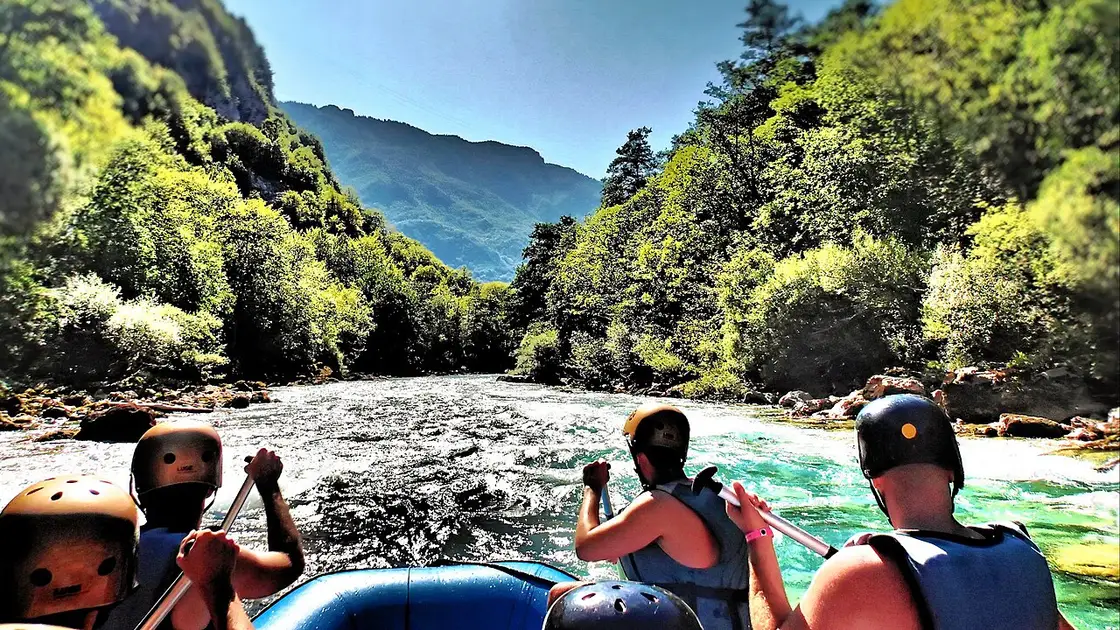 A raft of paddlers in helmets and life jackets punching through white water in the Tara canyon on the Bosnia-Montenegro border