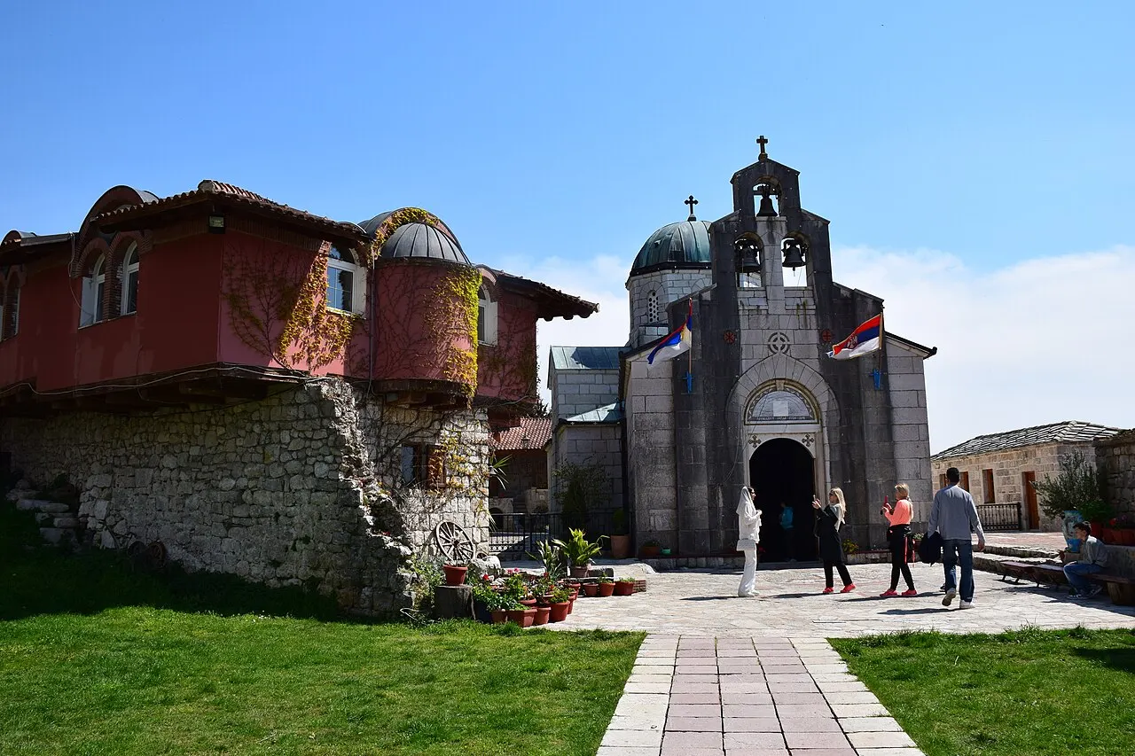 The stone courtyard and church of Tvrdos Monastery near Trebinje, with visitors in front of the entrance