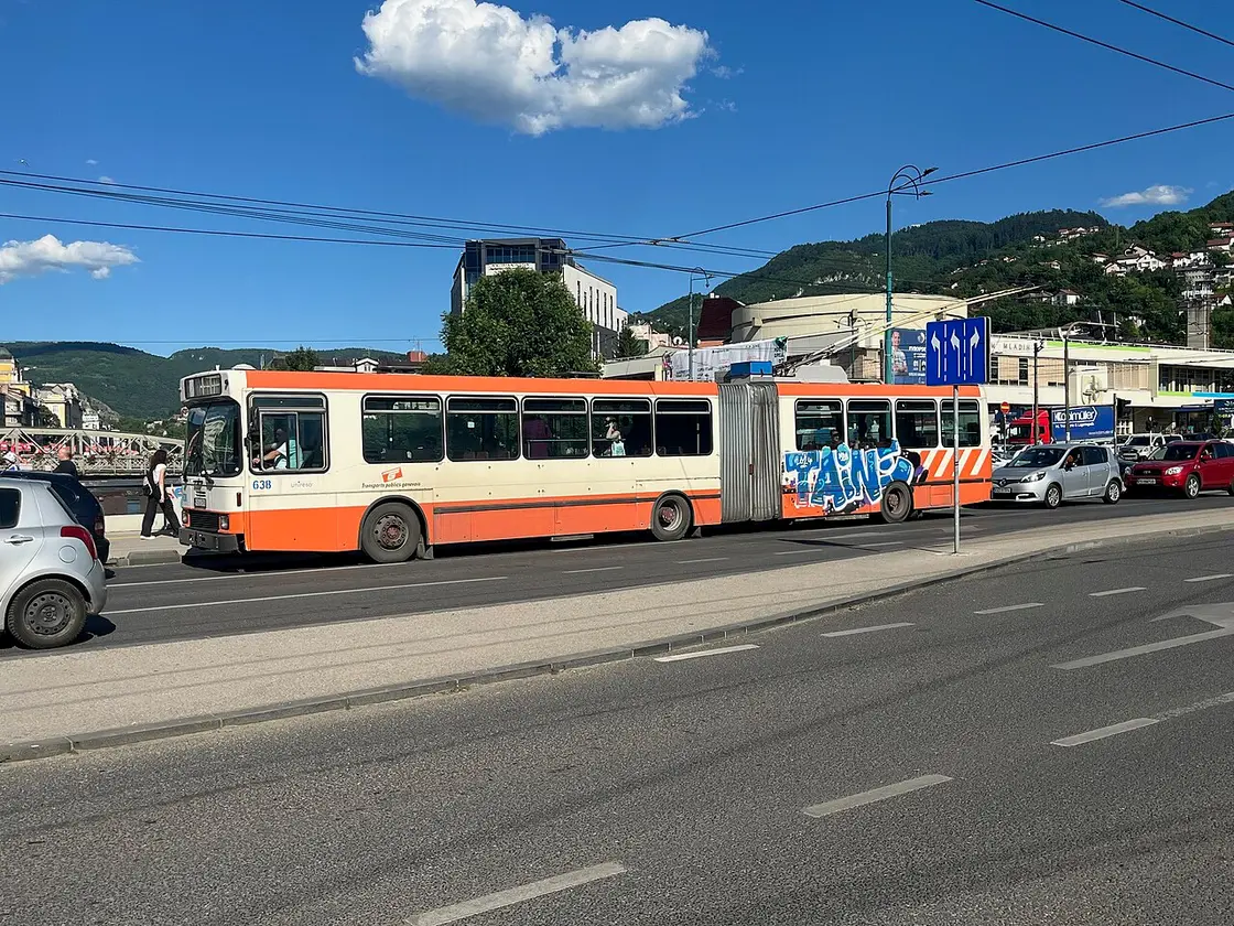 An articulated Sarajevo trolleybus on a city street with the hills behind, the cheap public transport that links the airport district to the centre