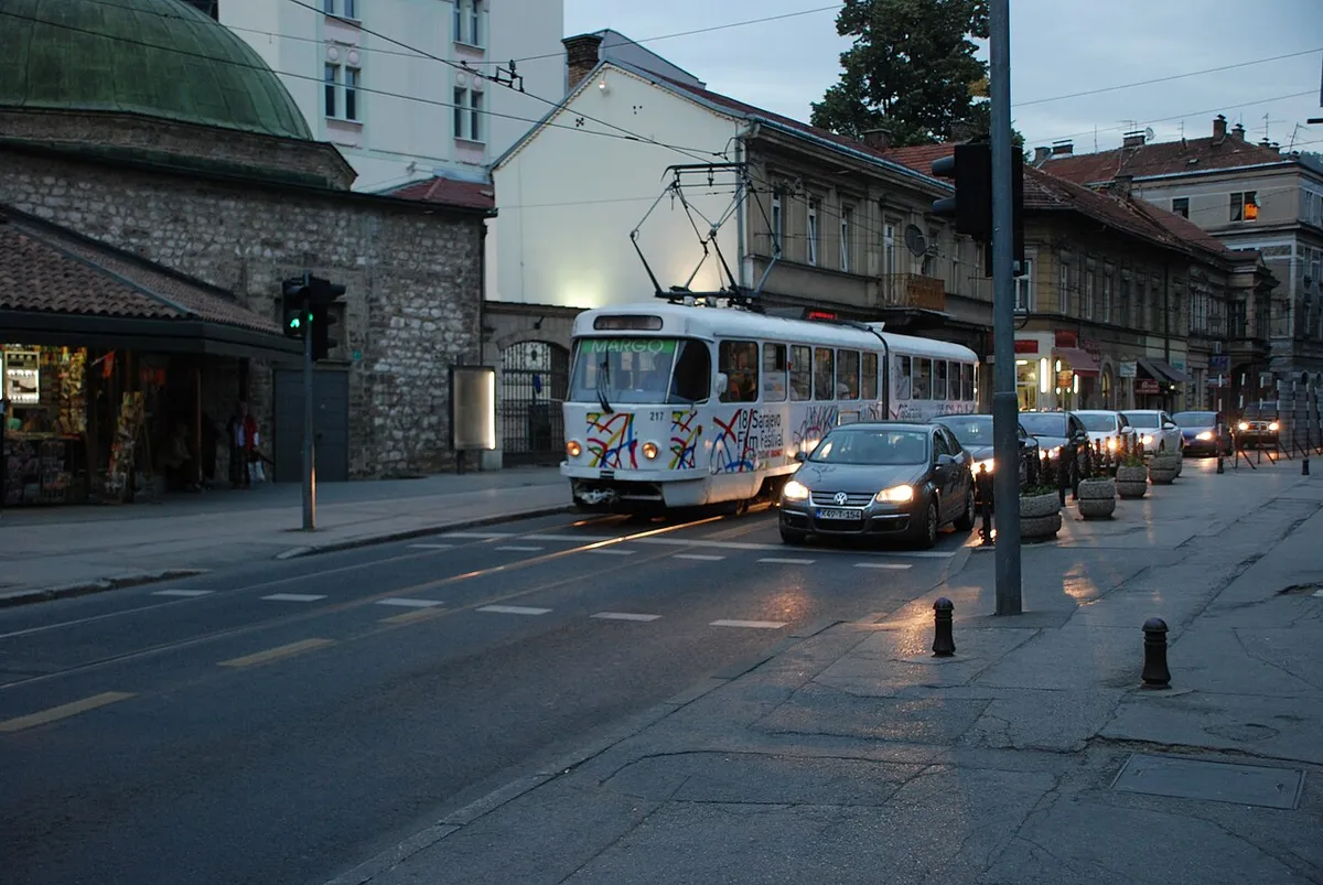 A Sarajevo tram wrapped in Sarajevo Film Festival livery on a city street at dusk, old town buildings behind
