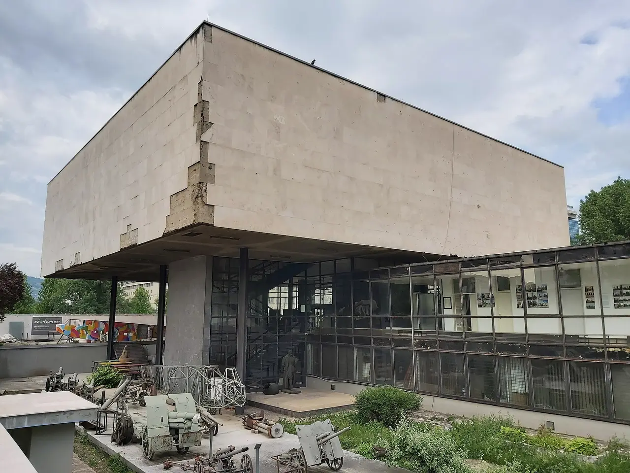 The brutalist concrete building of the Historical Museum of Bosnia and Herzegovina with old artillery pieces in the yard