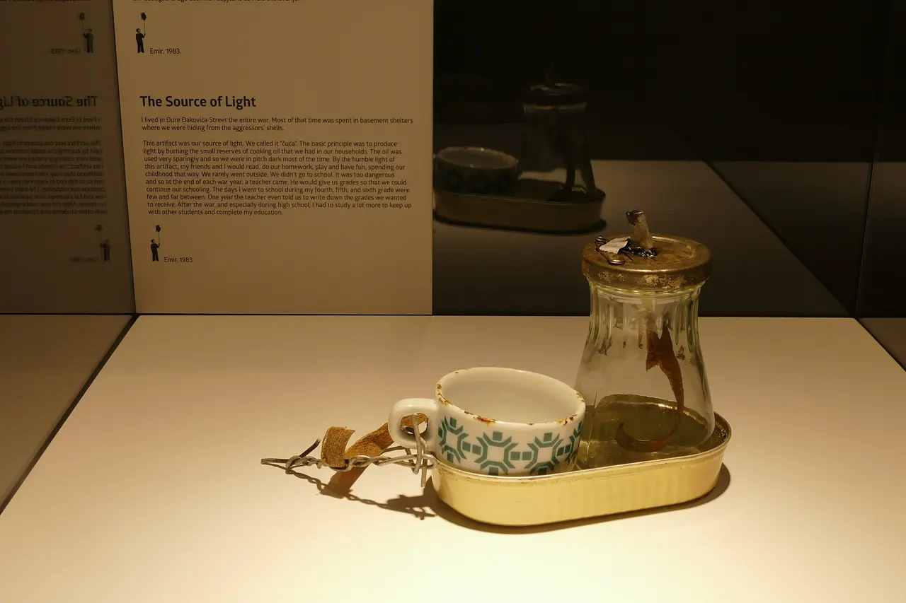 A museum display of an improvised oil lamp made from a jar and tin, with a written testimony titled The Source of Light