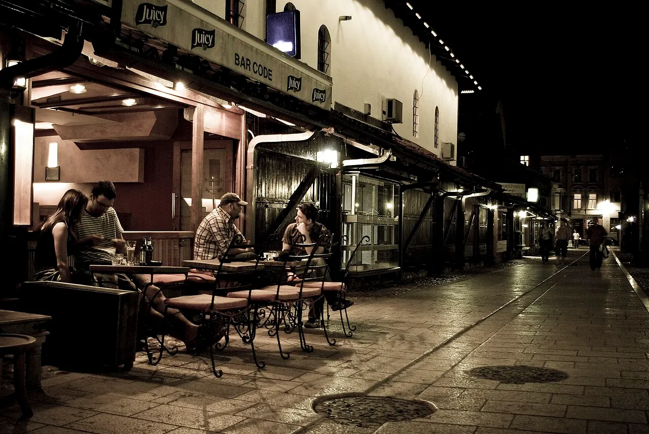Shopfront lights and people on a cobbled street in Sarajevo Old Town after dark