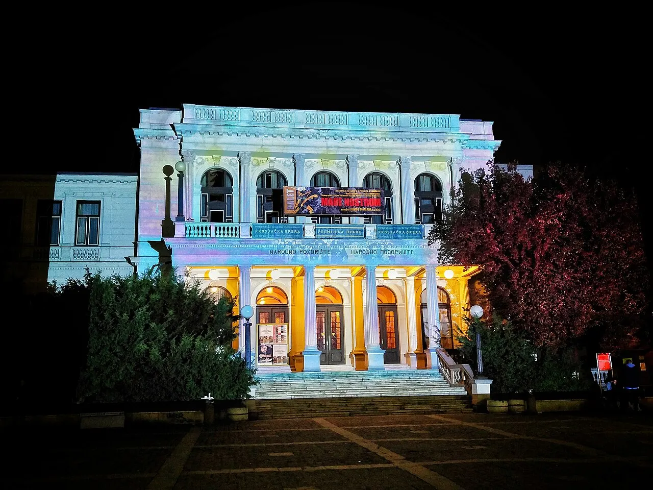 The National Theatre in Sarajevo glowing cream and gold against a black night sky