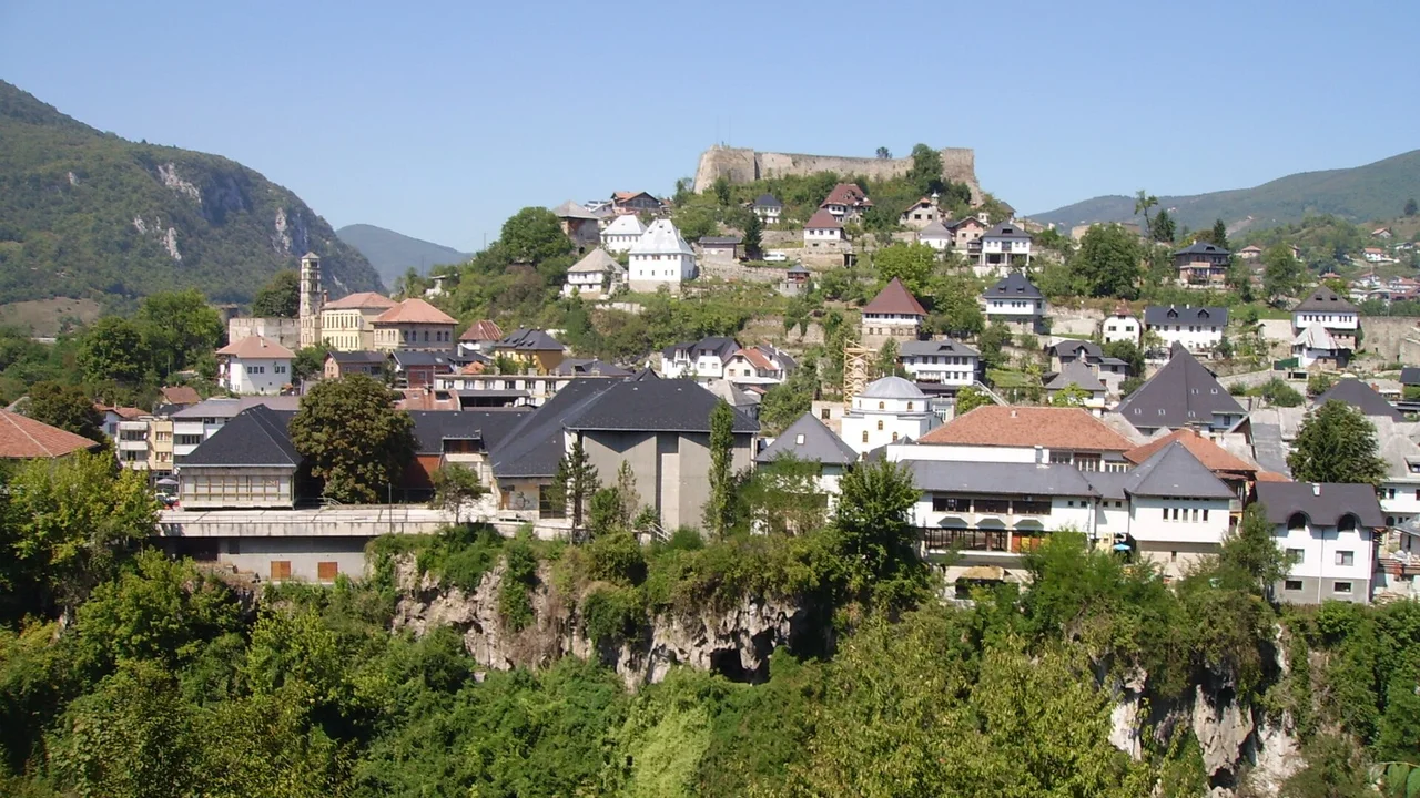 The town of Jajce on its rock, red roofs climbing to the fortress walls on the crest, karst cliffs below