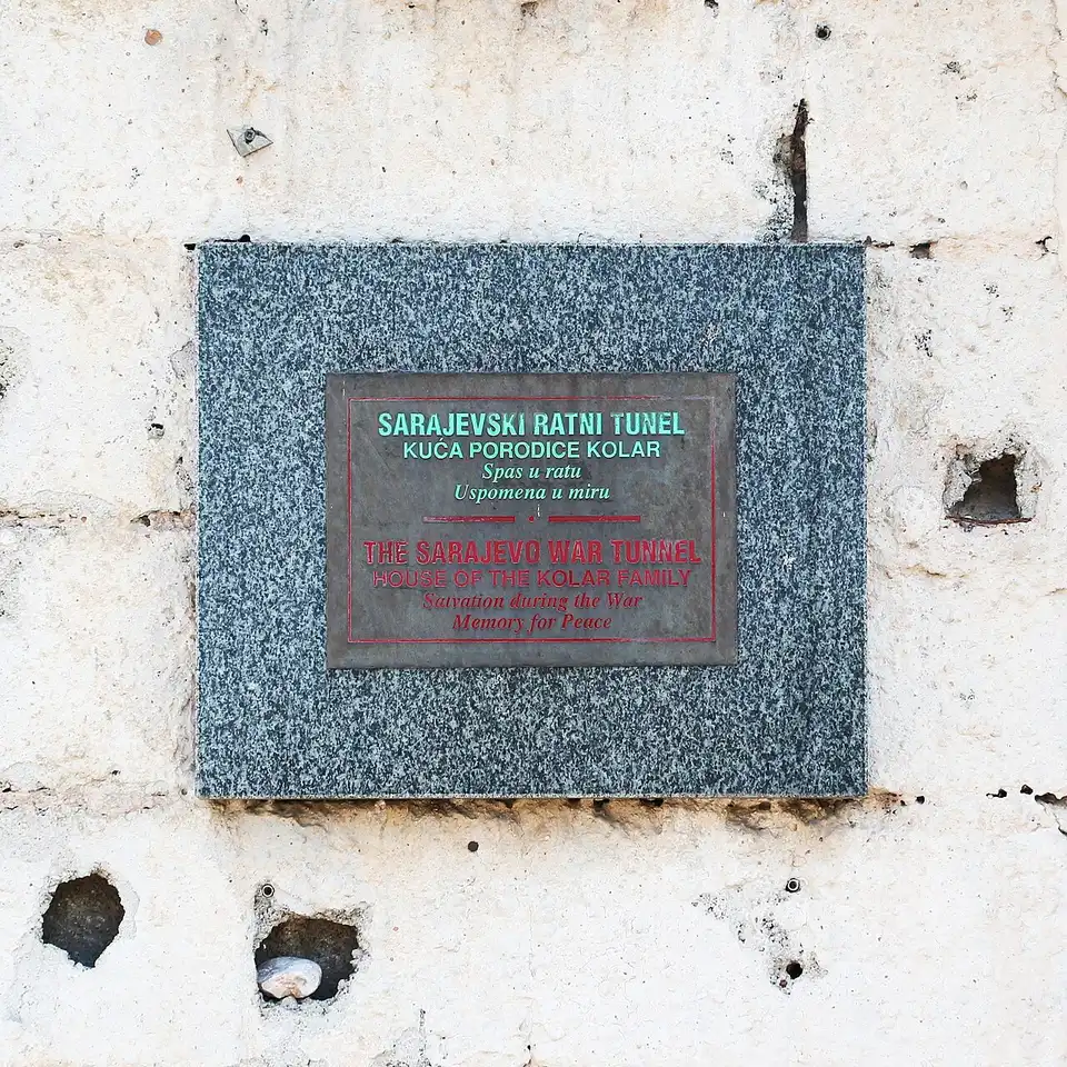 A bilingual plaque on the Kolar house reading The Sarajevo War Tunnel, House of the Kolar Family, Salvation during the War, Memory for Peace
