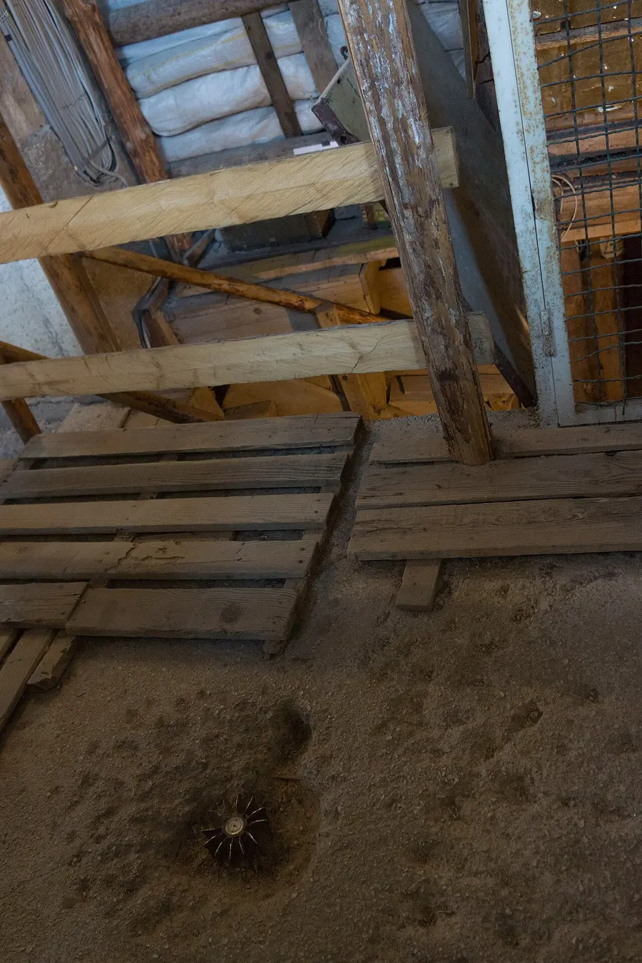 The timbered mouth of the Sarajevo tunnel with wooden props, sandbags and a spent mortar-shell fin on the earthen floor