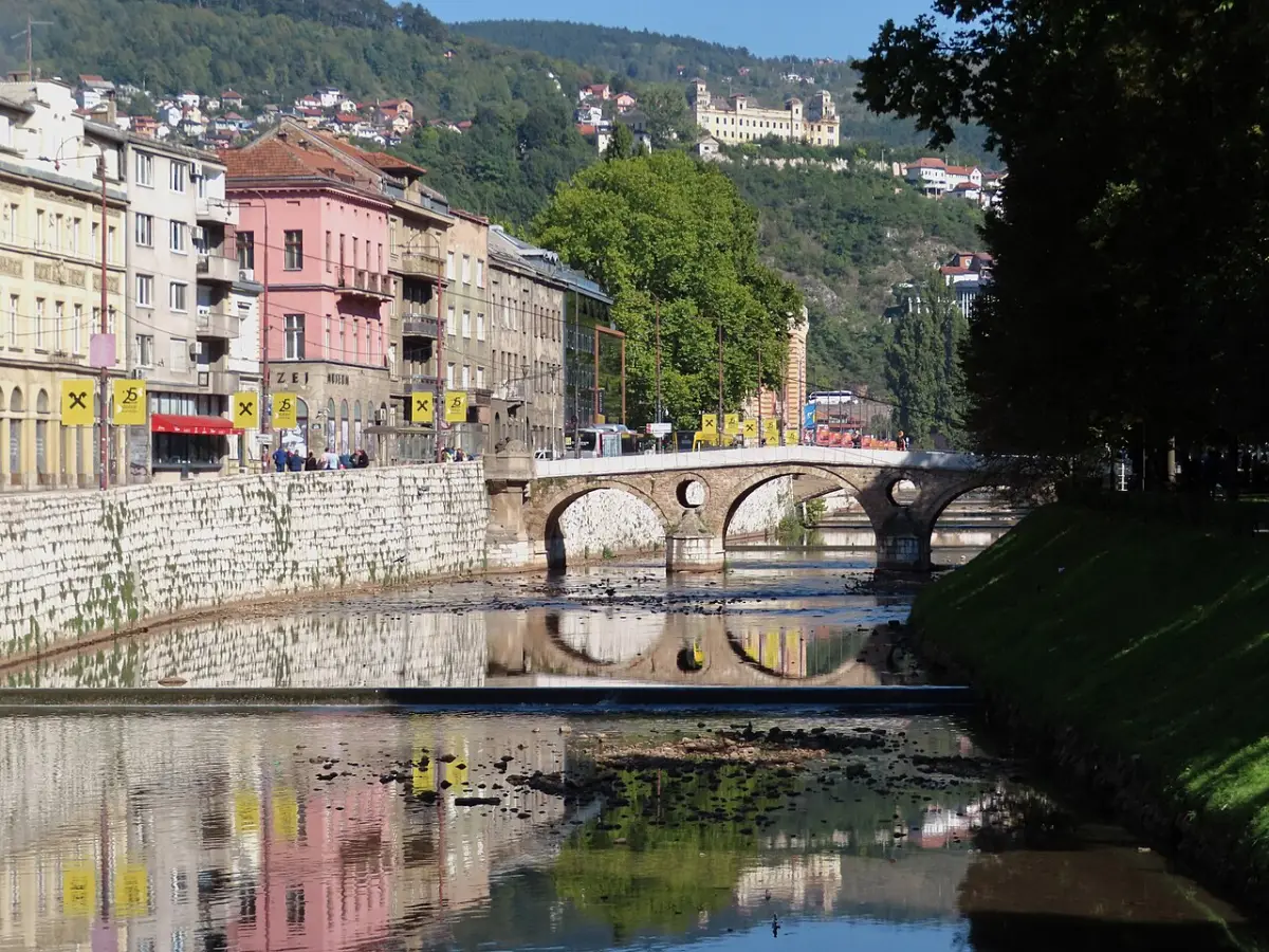 The stone Latin Bridge spanning the Miljacka river in Sarajevo with hillside houses rising behind