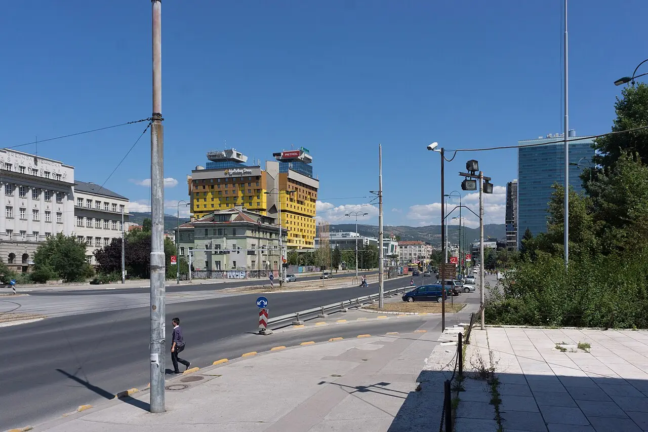 The yellow former Holiday Inn on the wide Zmaja od Bosne boulevard in Sarajevo, high-rise blocks beyond