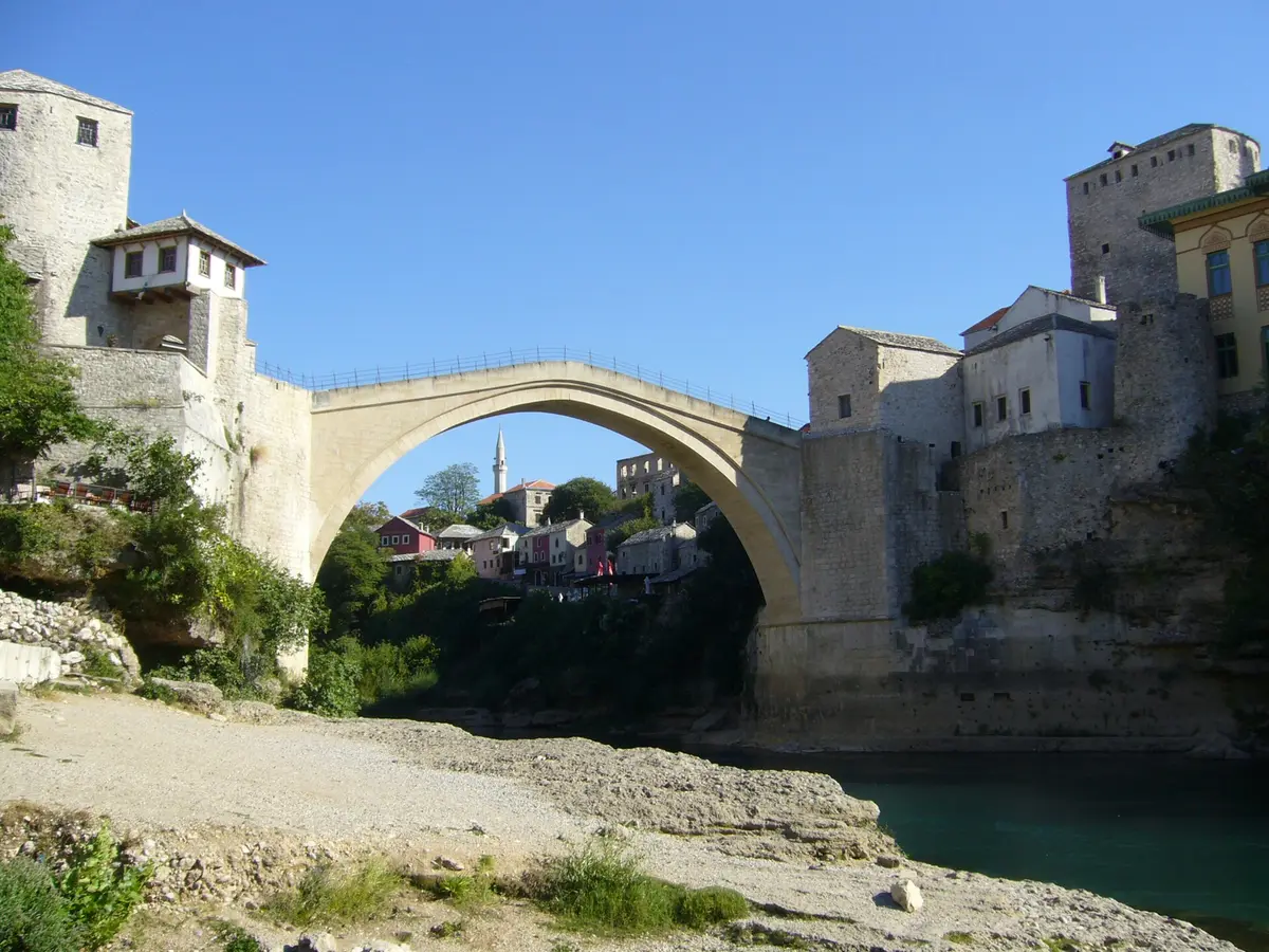 The Old Bridge of Mostar arcing over the green Neretva in morning light, the natural halfway break on the road from Split to Sarajevo