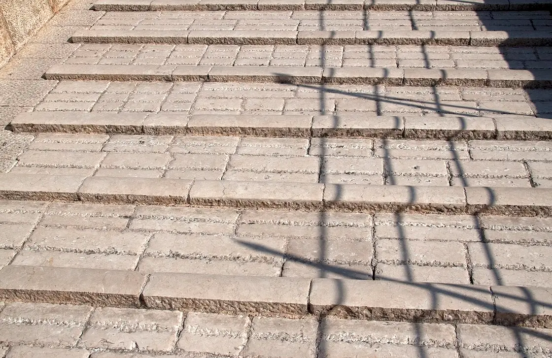The worn, domed limestone deck of Stari Most with raised stone ridges for grip, people crossing the steep arch