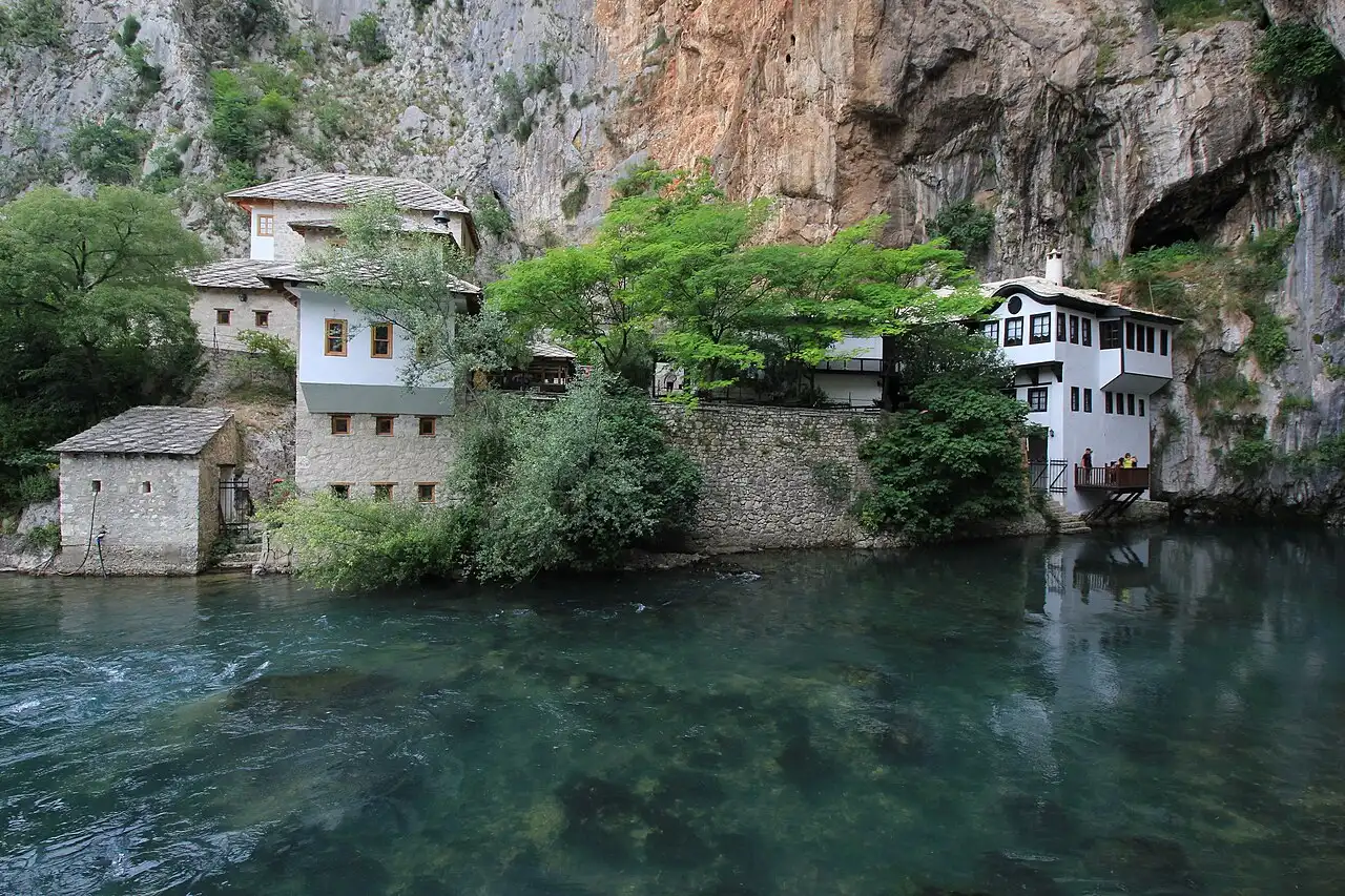 The white Blagaj dervish house tucked against a huge limestone cliff above the clear green Buna river