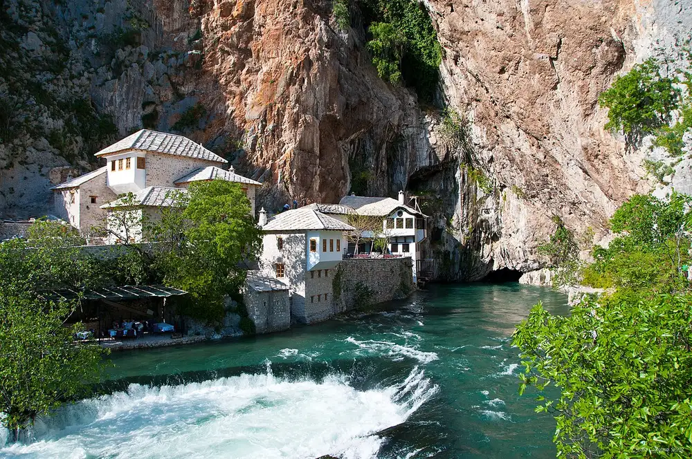 The white Blagaj Tekija dervish house at the foot of a cliff where the Buna river emerges from a cave