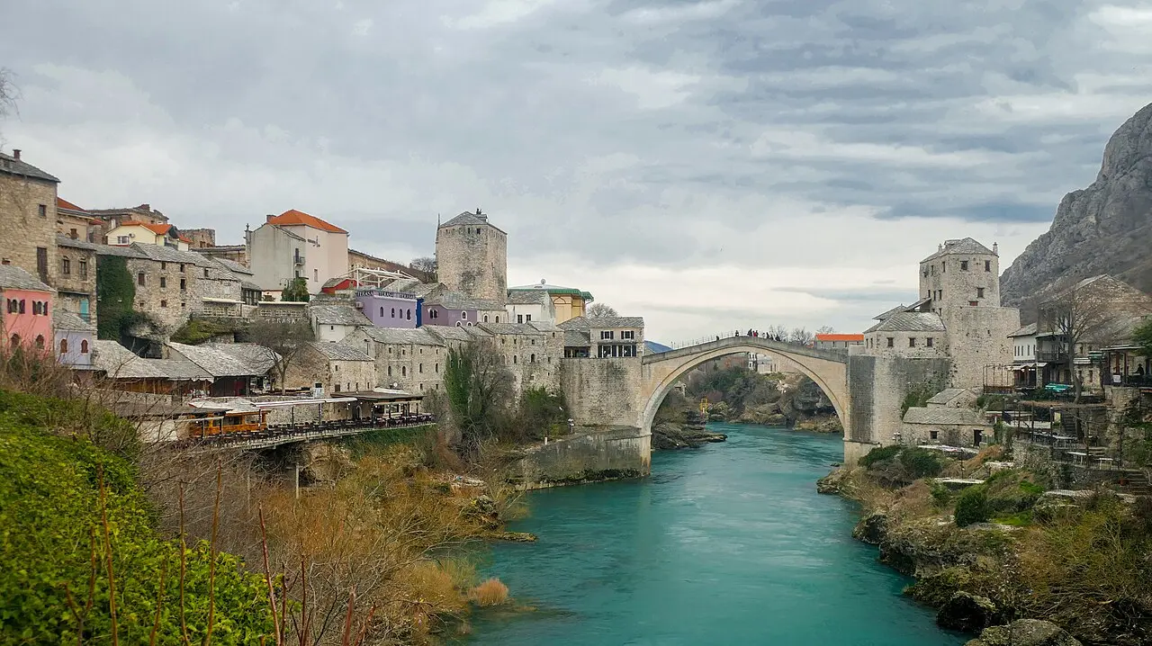 The single stone arch of Stari Most, the Old Bridge of Mostar, rising over the green Neretva between two stone towers