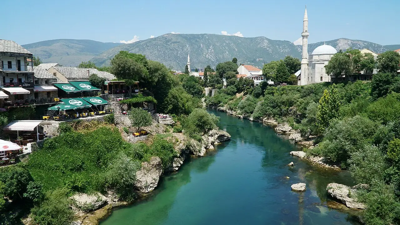 The domed Koski Mehmed-Paša Mosque and its minaret on the bank of the Neretva in Mostar