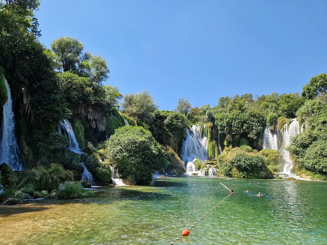 The wide horseshoe of Kravice Waterfalls tumbling into a green pool in Herzegovina