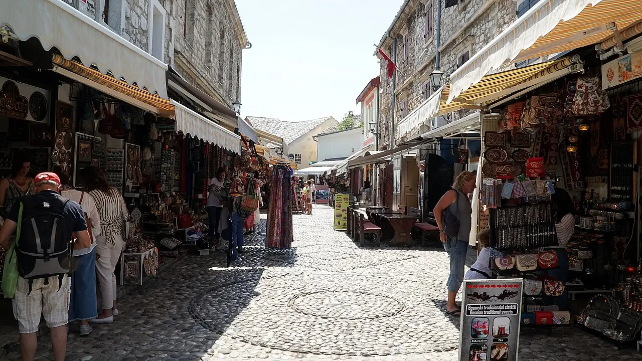 The cobbled Kujundžiluk bazaar street in Mostar lined with copper stalls, leading towards a minaret