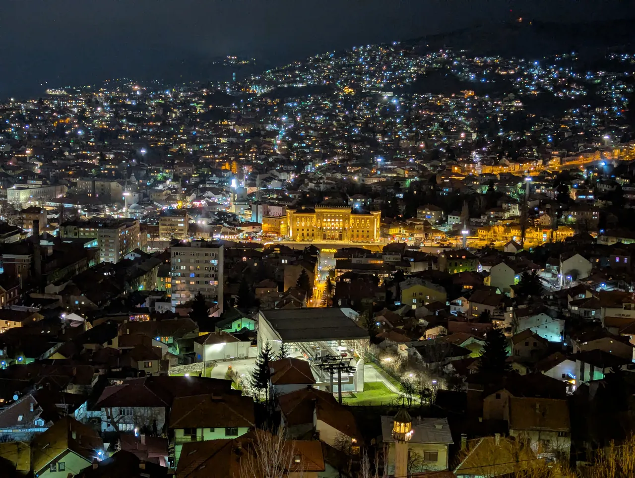 Sarajevo lit up at night, seen from a hillside above the valley