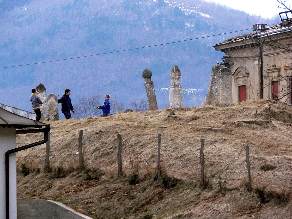 Old Ottoman gravestones on a grassy hillside in a Travnik mahala, children playing among them