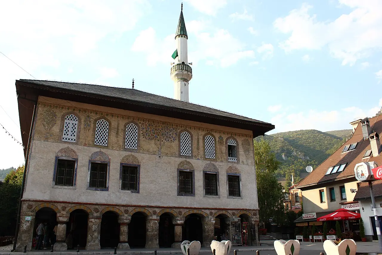 The two-storey Sarena Dzamija in Travnik, its painted prayer hall raised over an arcaded ground floor of shops, minaret behind