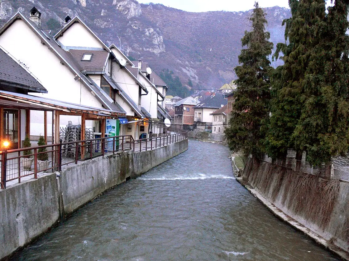 The Lasva river running past cafe terraces and old houses in Travnik under winter mountains