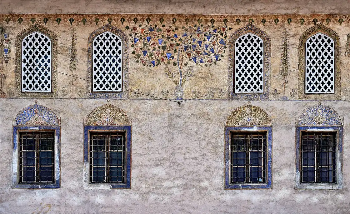 Faded painted floral motifs and arched lattice windows on the facade of the Sarena Dzamija in Travnik