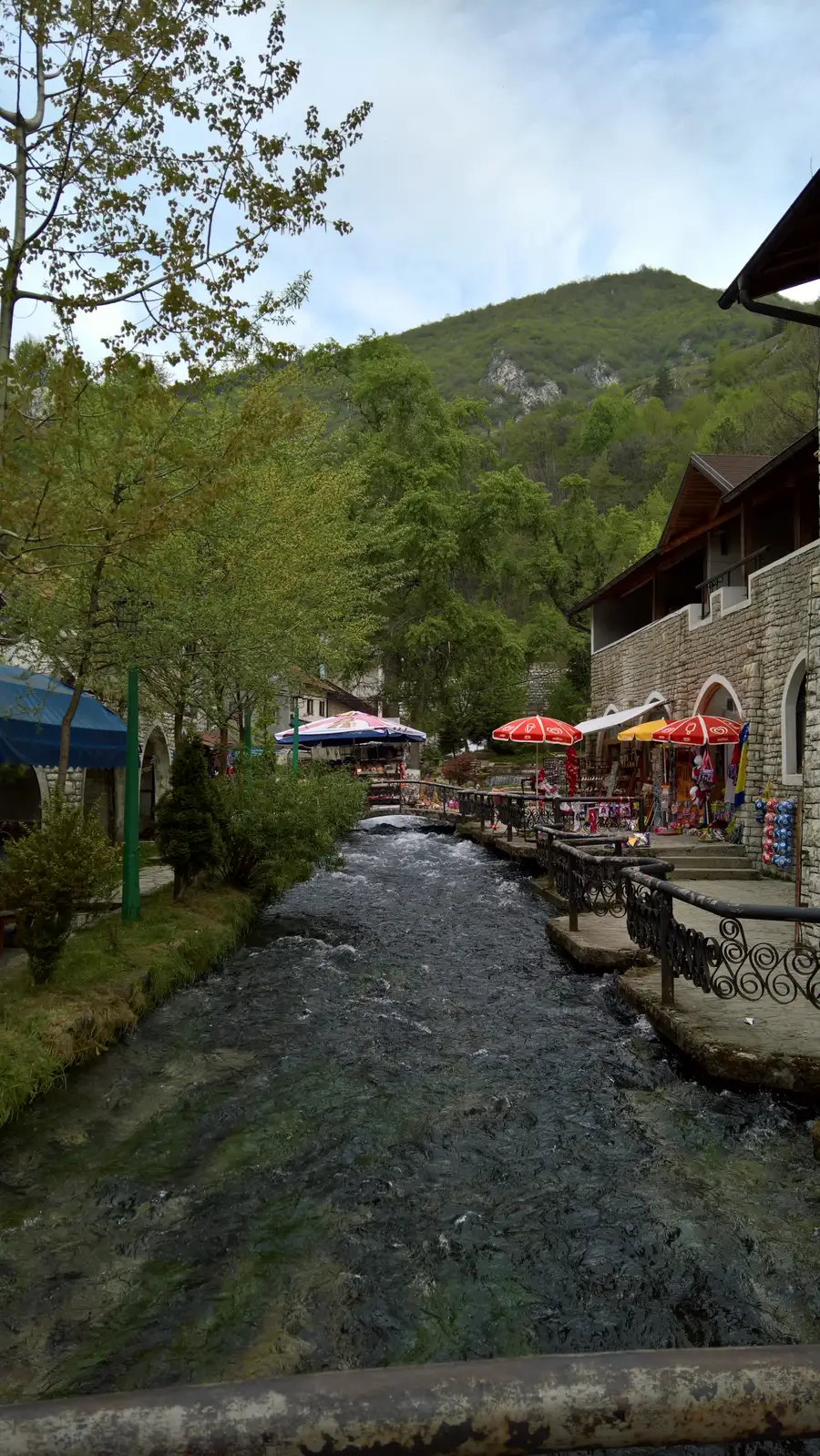 The clear Plava Voda stream running between cafes and stone houses in Travnik, wooden footbridges crossing it