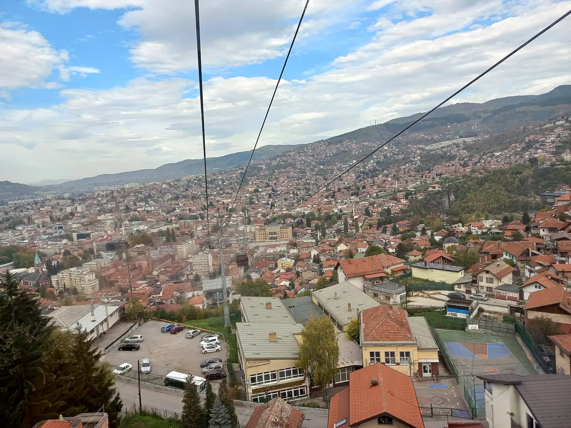 The view down over the red rooftops of Sarajevo old town from a descending cable car cabin