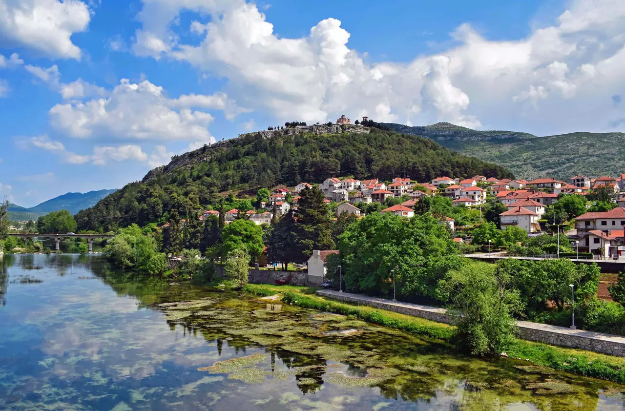 View across the green Trebišnjica river to the old town of Trebinje and the mountains behind
