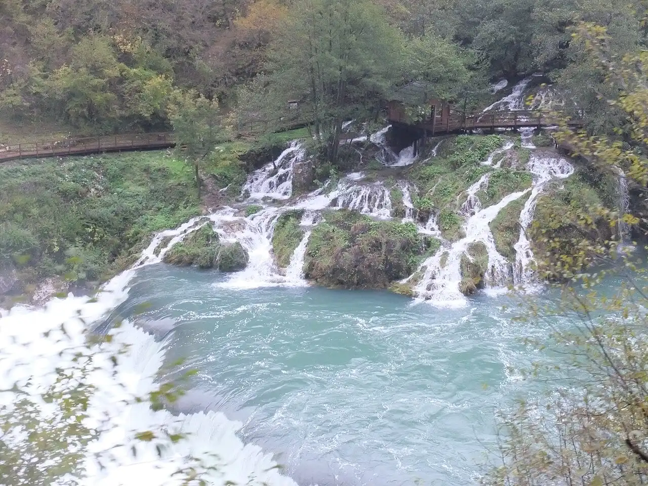 Cascades and clear green pools of the Una river within Una National Park, thick forest on the banks