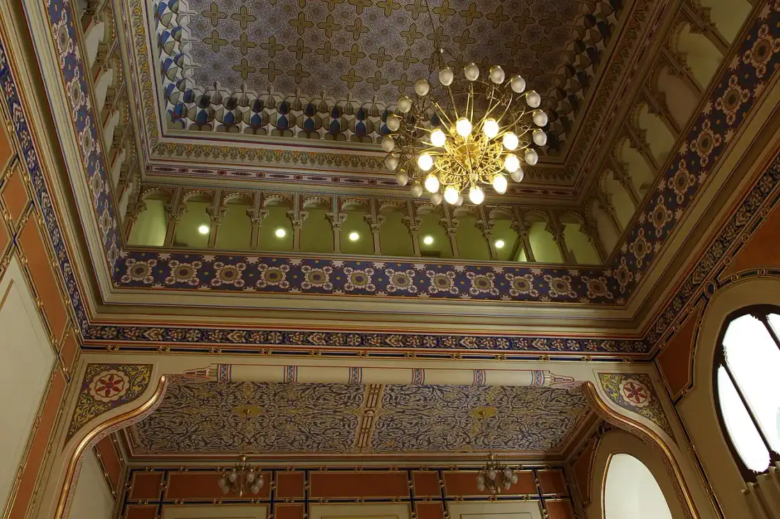 Looking up at the geometric stained-glass roof of Sarajevo City Hall from the atrium floor