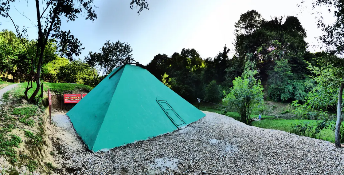 A small green-painted concrete pyramid model built at the tunnel park entrance near Visoko
