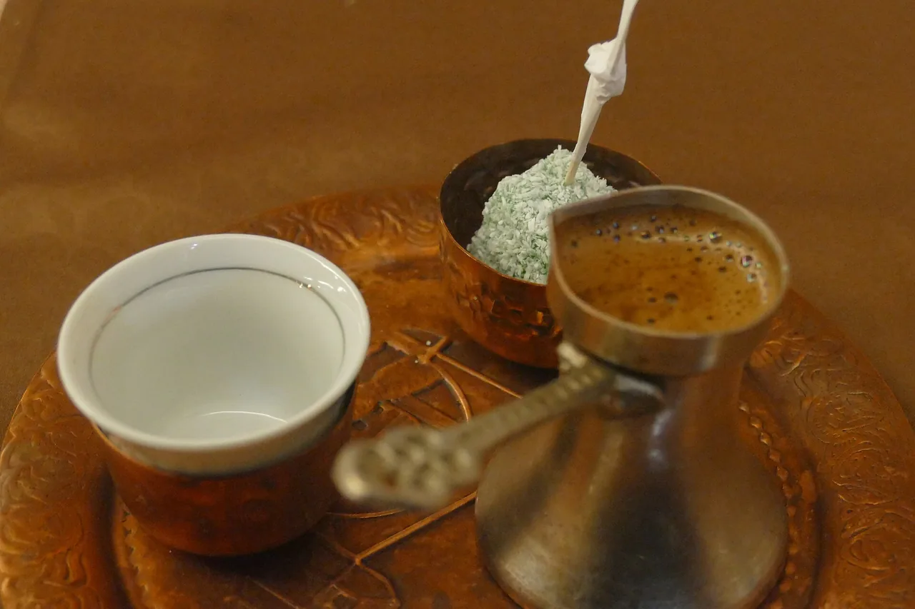 A Bosnian coffee set on an engraved copper tray: a copper džezva with foam, a handleless fildžan cup, and rahat lokum