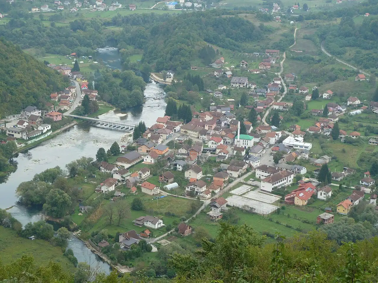 Houses of Kulen Vakuf beside the clear Una river with a small weir and green hills