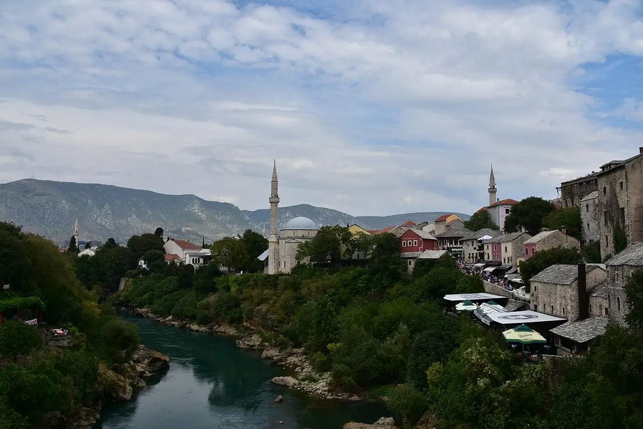 A view along the Neretva in Mostar past the Koski Mehmed-Pasa mosque dome and minaret to riverside houses and restaurants on the east bank