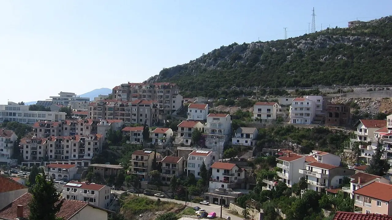 The hillside of Neum densely packed with white apartment buildings, guesthouses and hotels dropping toward the sea