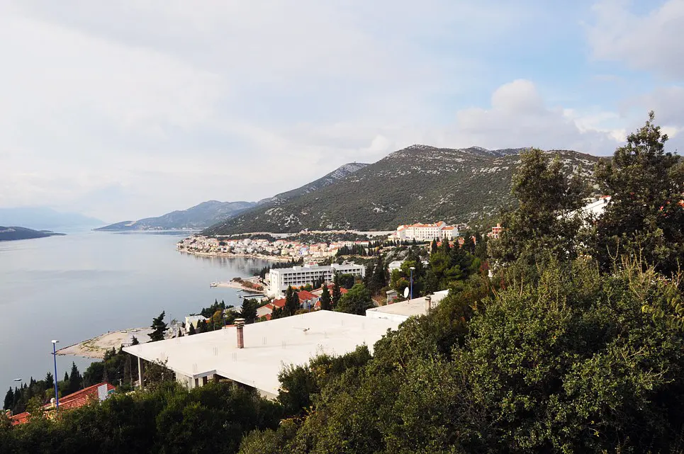 Elevated view of Neum with its large seafront hotel blocks and the town spread along the shore below wooded hills