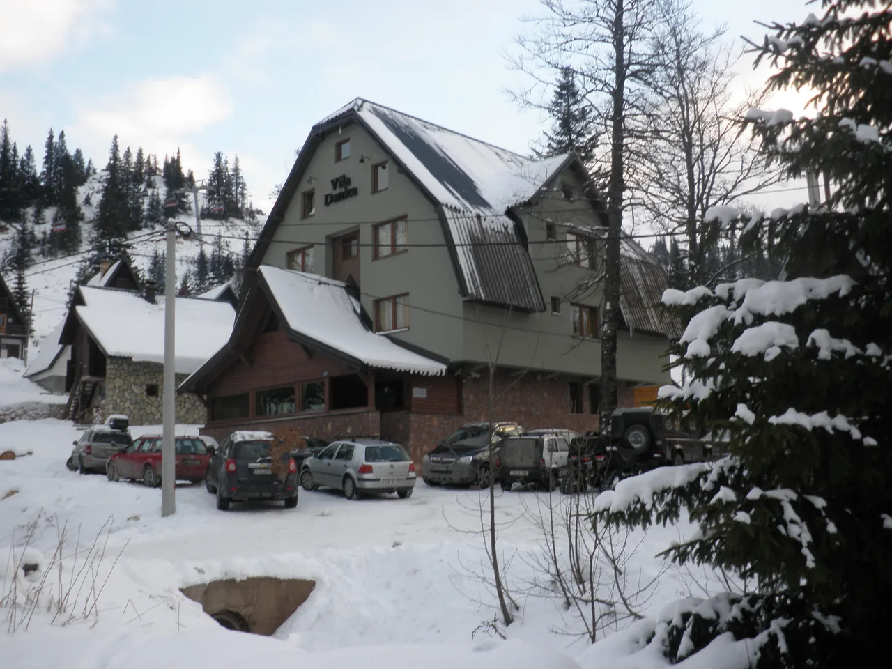 An apartment villa on the Jahorina mountain road with cars parked in the snow outside