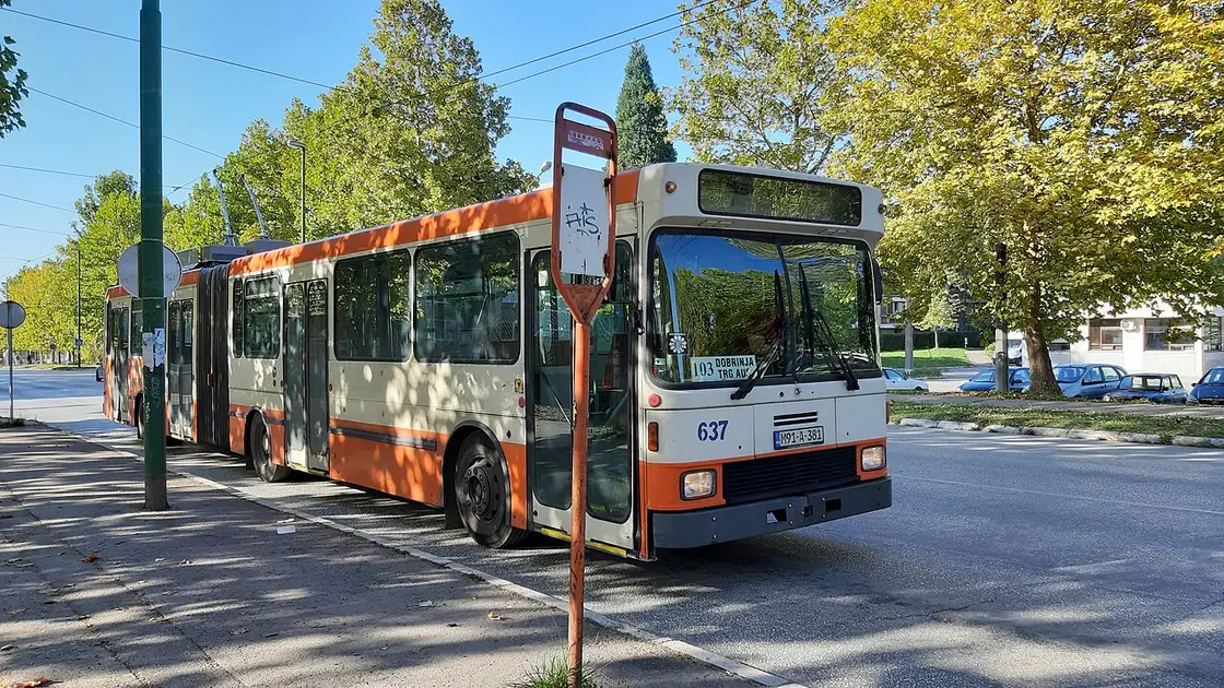 A red and white trolleybus on a Sarajevo street, part of the public transport that links the airport district to the city centre